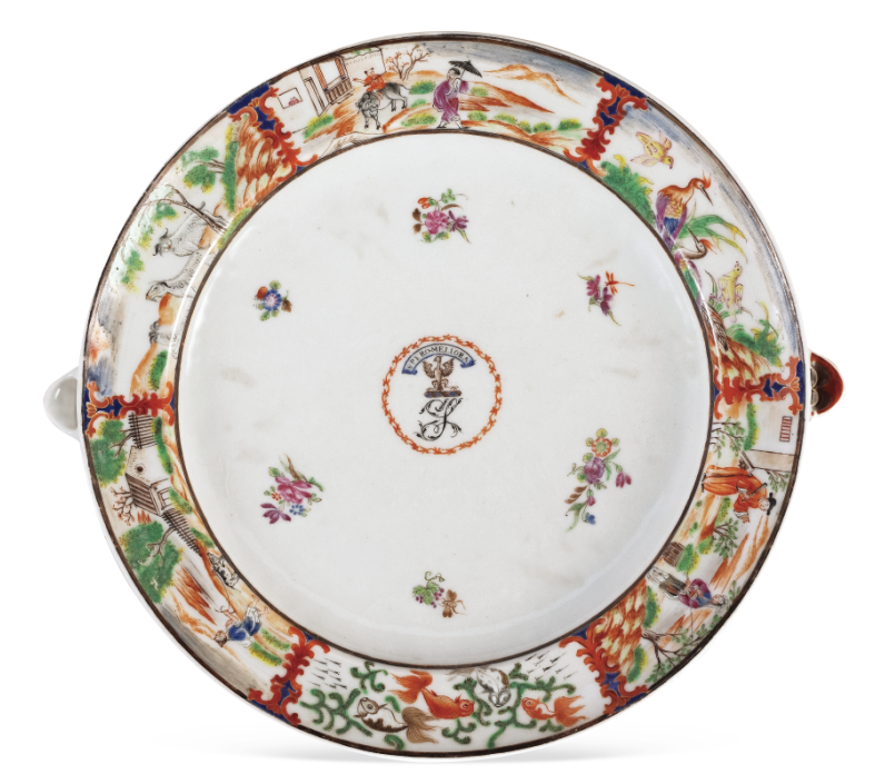 圖為清嘉慶廣彩描金花卉人物紋章溫盤，盤沿兩側對稱置半圓形注水口。外邊飾為鄉(xiāng)村風景紋，盤心繪紋章，四周繪六組折枝花卉圍繞。溫盤又稱暖盤，使用時將熱水由孔注入，使盛入淺盤的食物保溫，達到防冷溫熱的效果。（來源：廣州十三行博物館）